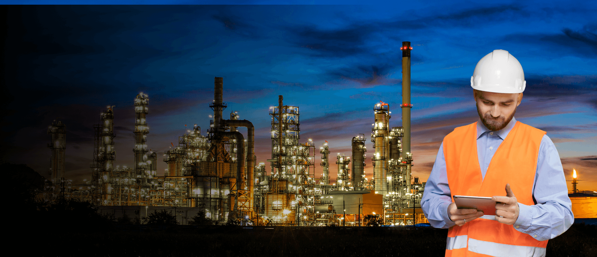 Oil refinery at dusk with an operations worker using a tablet