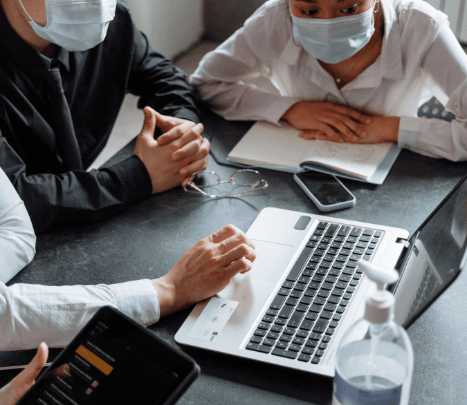 Healthcare team collaborating around a table with laptops and reports